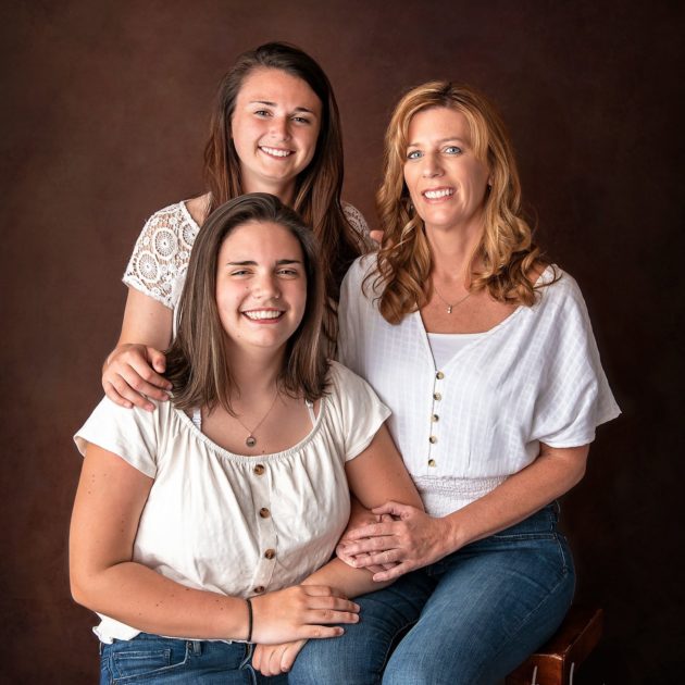 Family photo of mother and daughters on brown backdrop