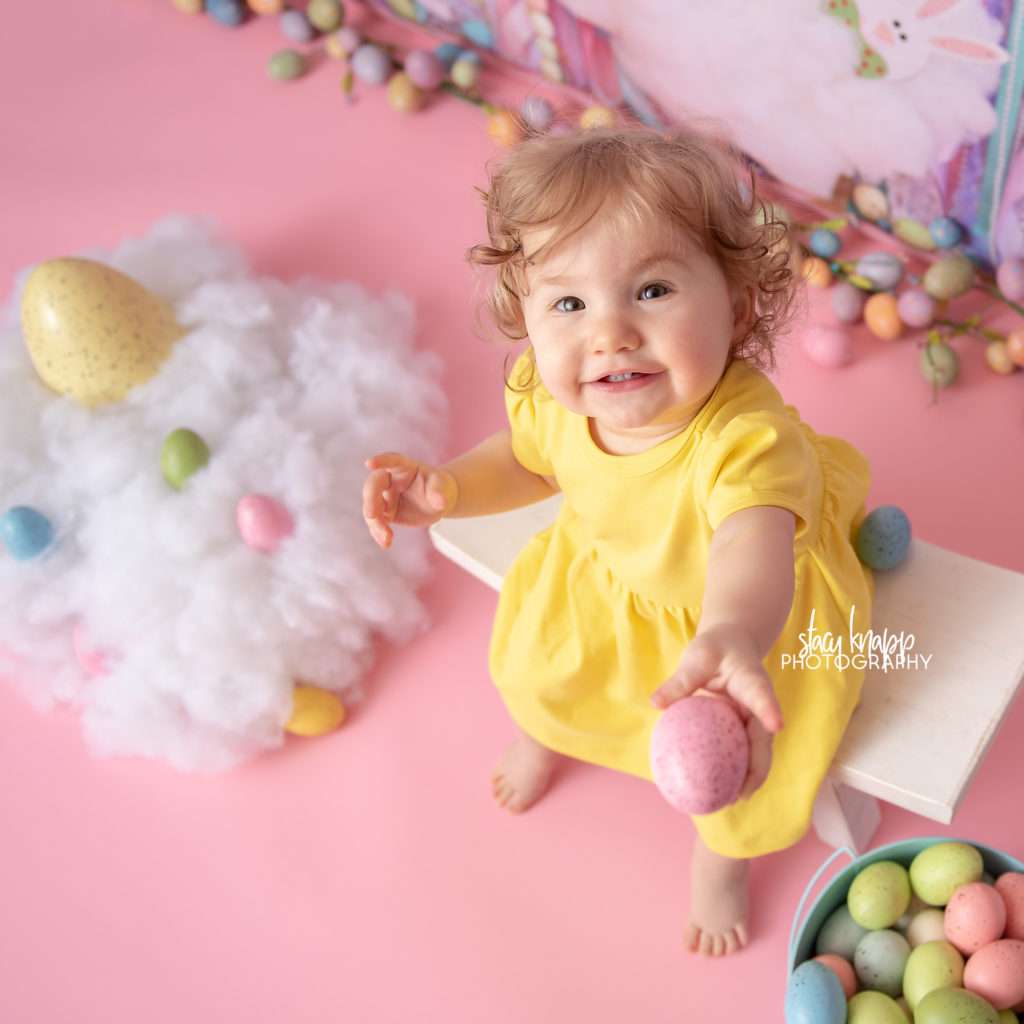 Baby girl Easter photograph on an Easter egg backdrop during a mini session