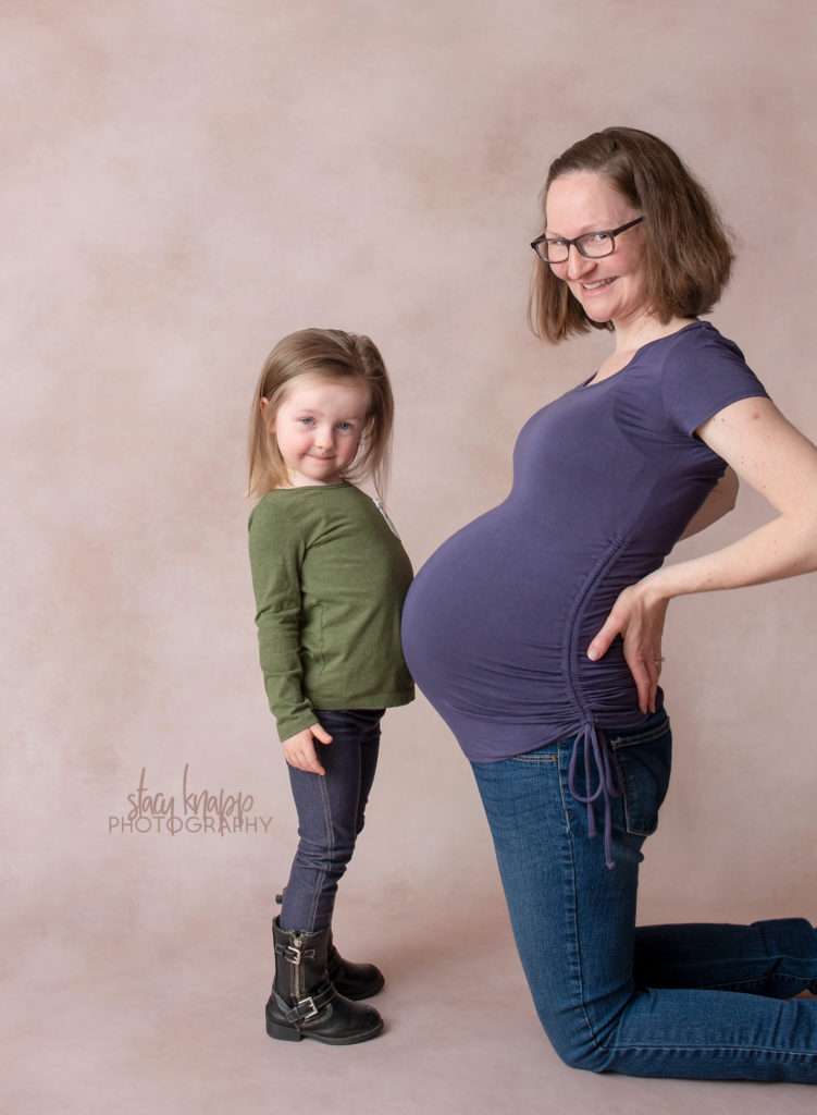 Maternity photo of mother and daughter bumping bellies
