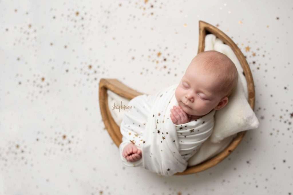 Photo of a Maine newborn baby girl by photographer Stacy Knapp Photography. Baby is in natural moon prop on a white and star background.