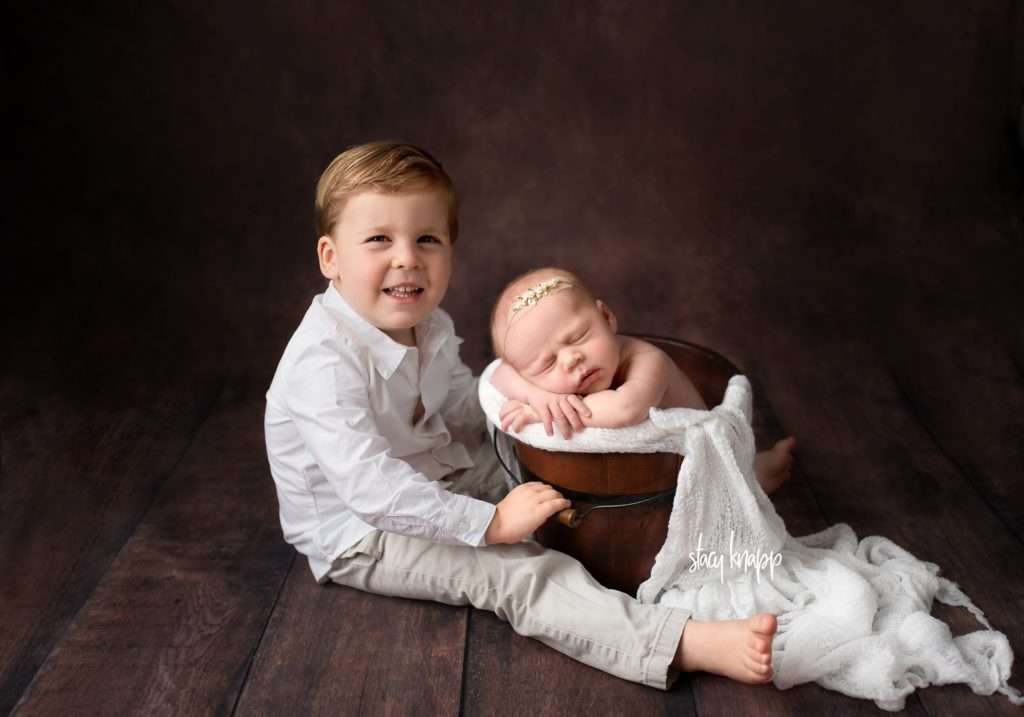 Toddler boy with baby newborn sister in a bucket
