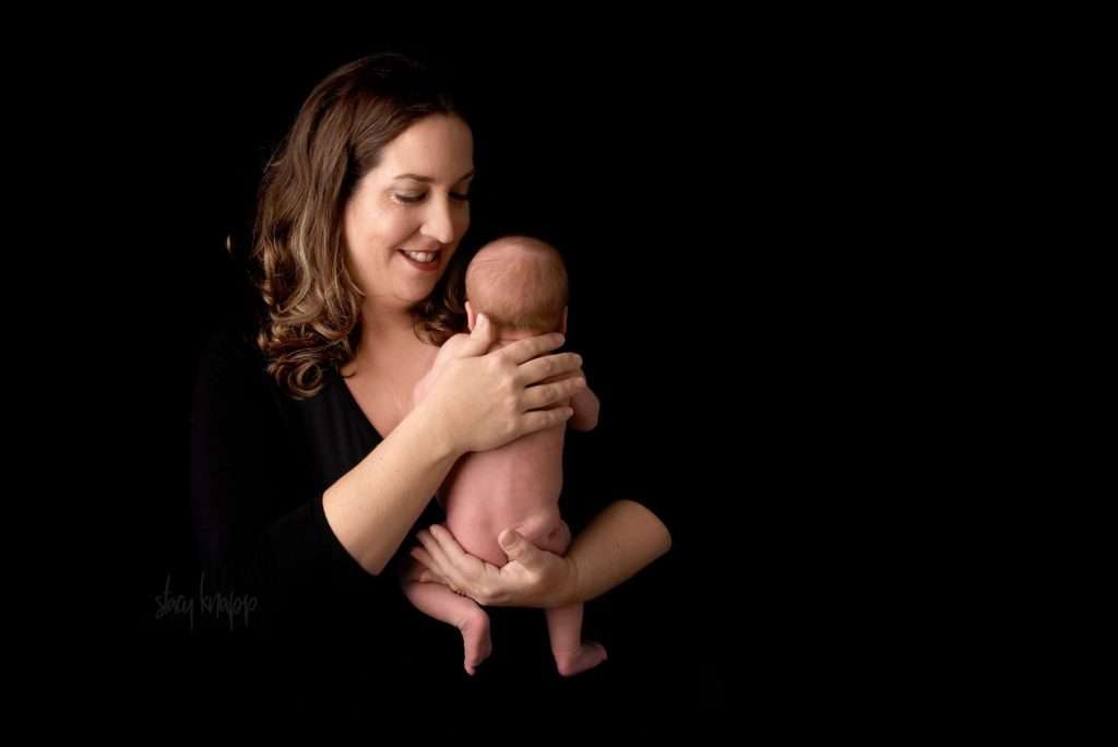 mom with newborn baby girl on black