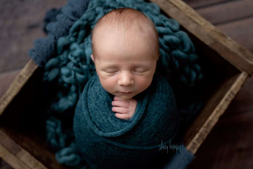 Maine newborn baby boy in turquoise in a wood crate by photographer Stacy Knapp Photography