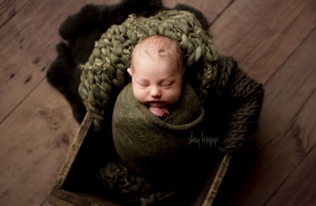 Newborn baby boy in green in wood crate