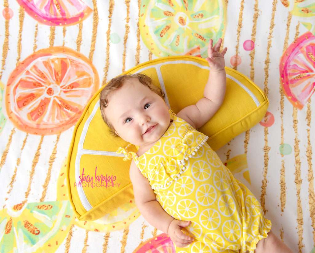 Baby girl photographed wearing lemon outfit on citrus backdrop