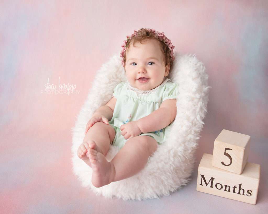 Five-month-old baby girl photographed on pink backdrop