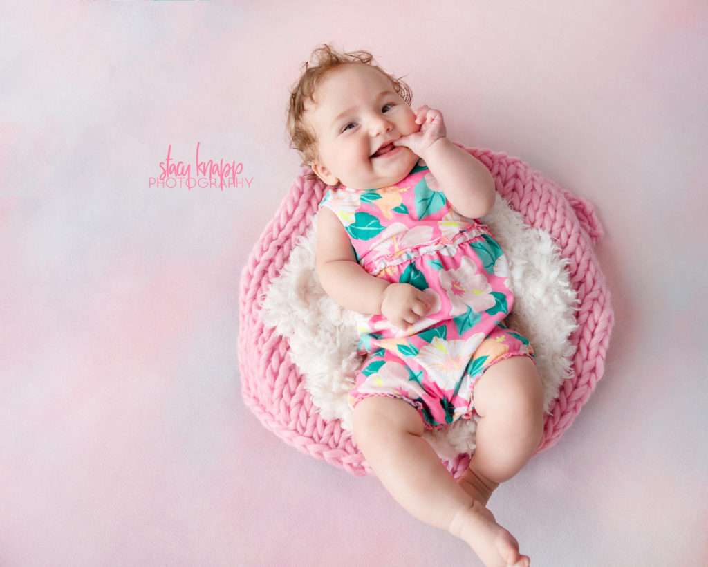Five-month-old baby girl photographed on pink backdrop