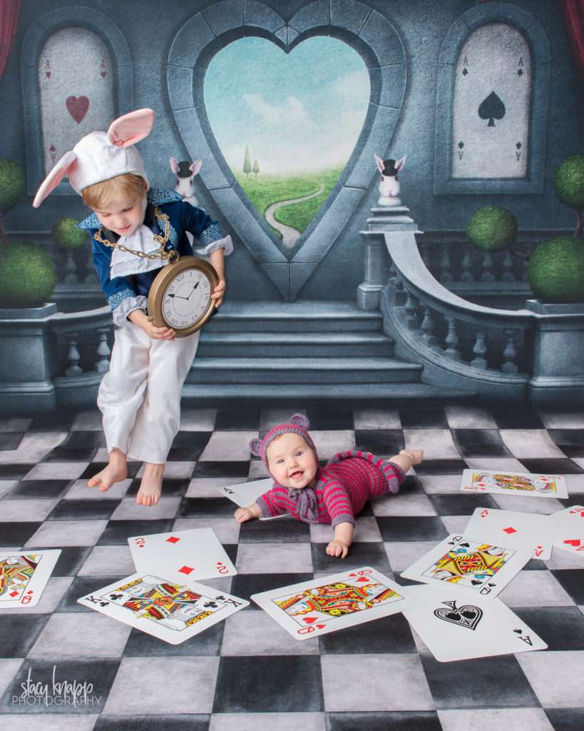 Brother and sister photographed on Alice in Wonderland backdrop