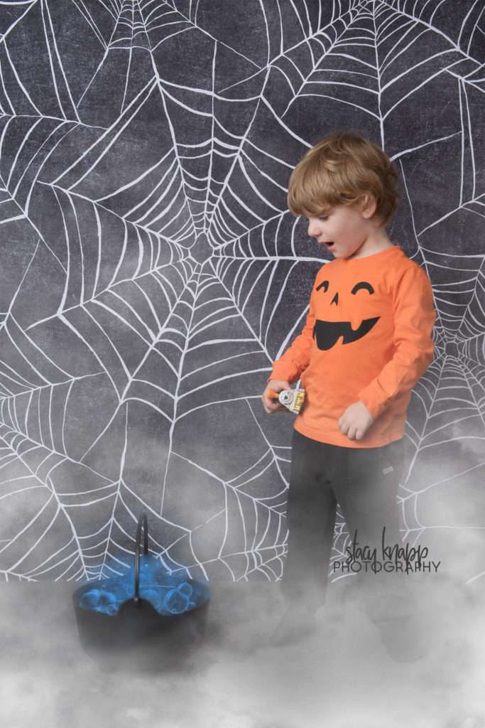 Preschool boy age three photographed on Halloween backdrop