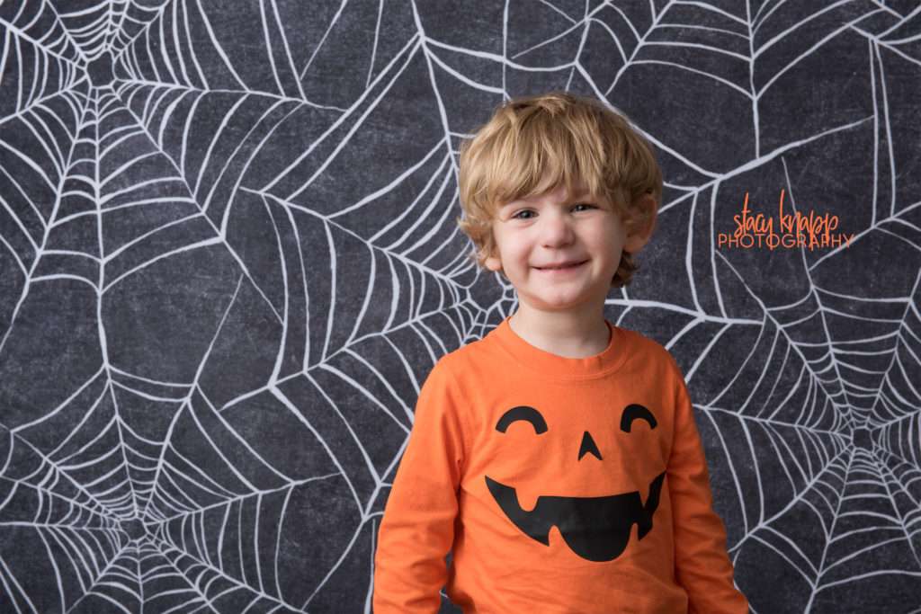 Preschool boy age three photographed on Halloween backdrop