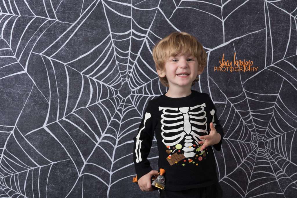 Preschool boy age three photographed on Halloween backdrop
