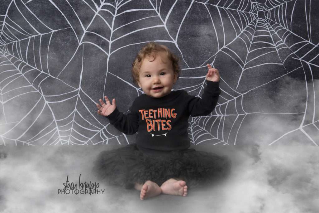 Baby girl photographed on Halloween backdrop wearing teething bites outfit