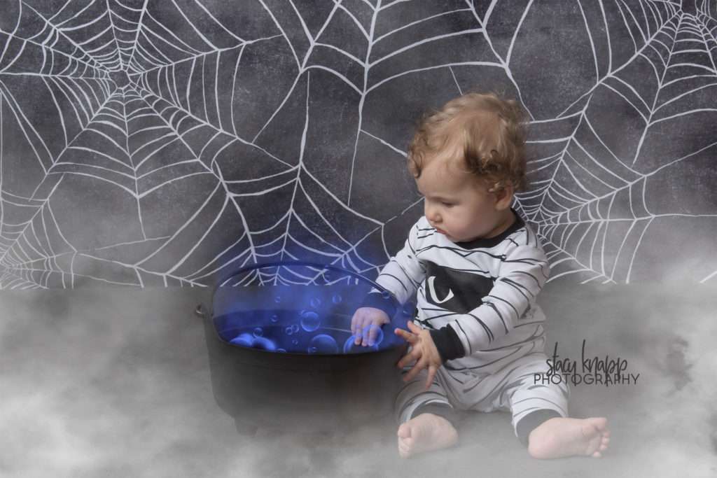 Baby girl photographed on Halloween backdrop wearing mummy outfit