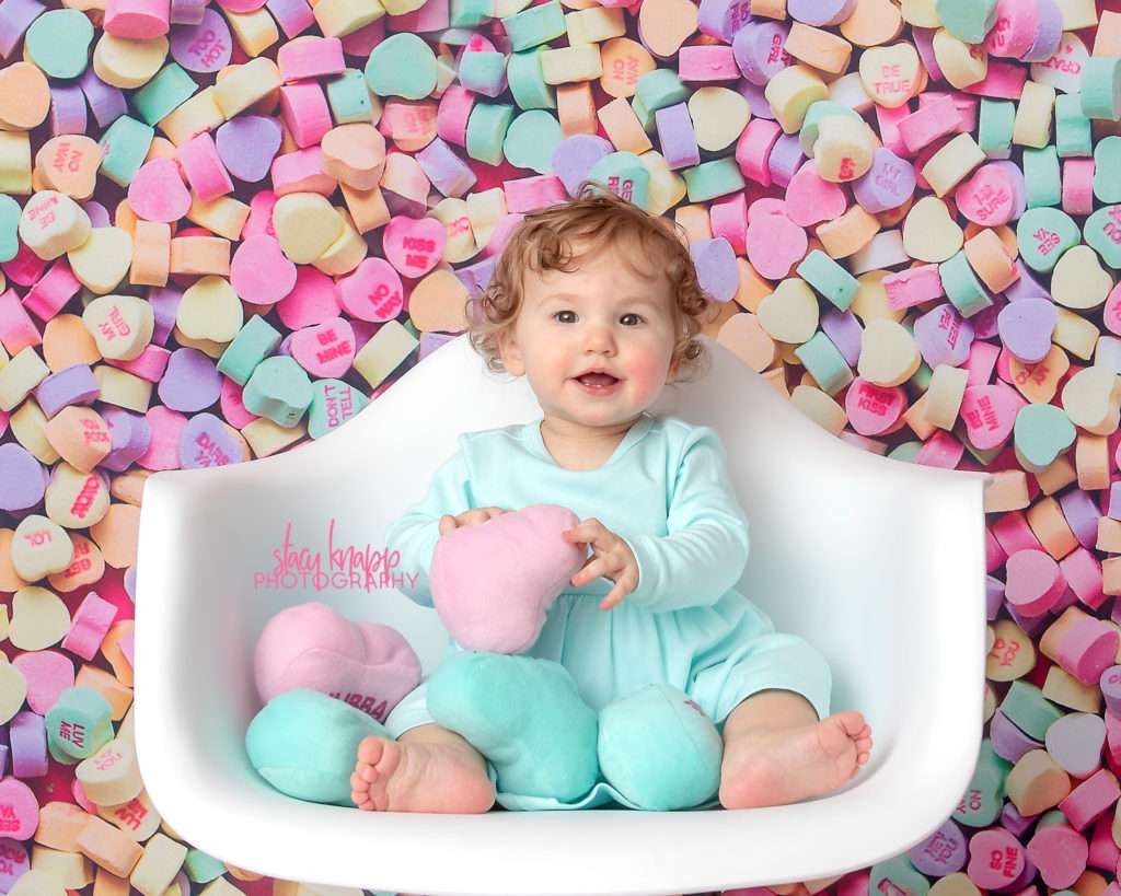 Baby girl photographed on candy heart backdrop during mini session