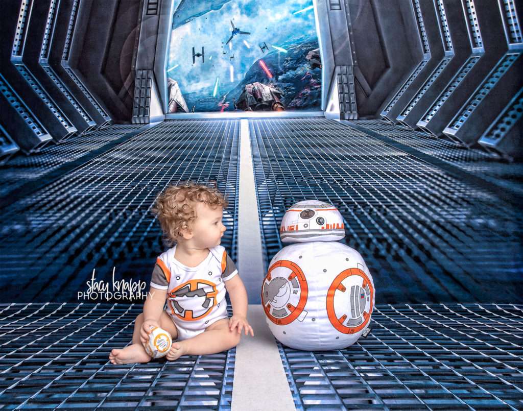 Baby girl photographed on Star Wars backdrop wearing BB8 outfit