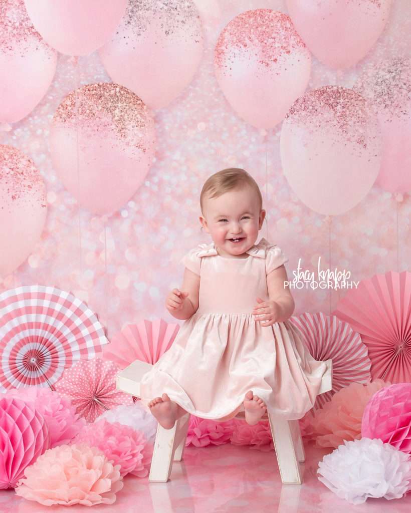 Photo of one-year-old girl birthday session with pink balloons and pink dress