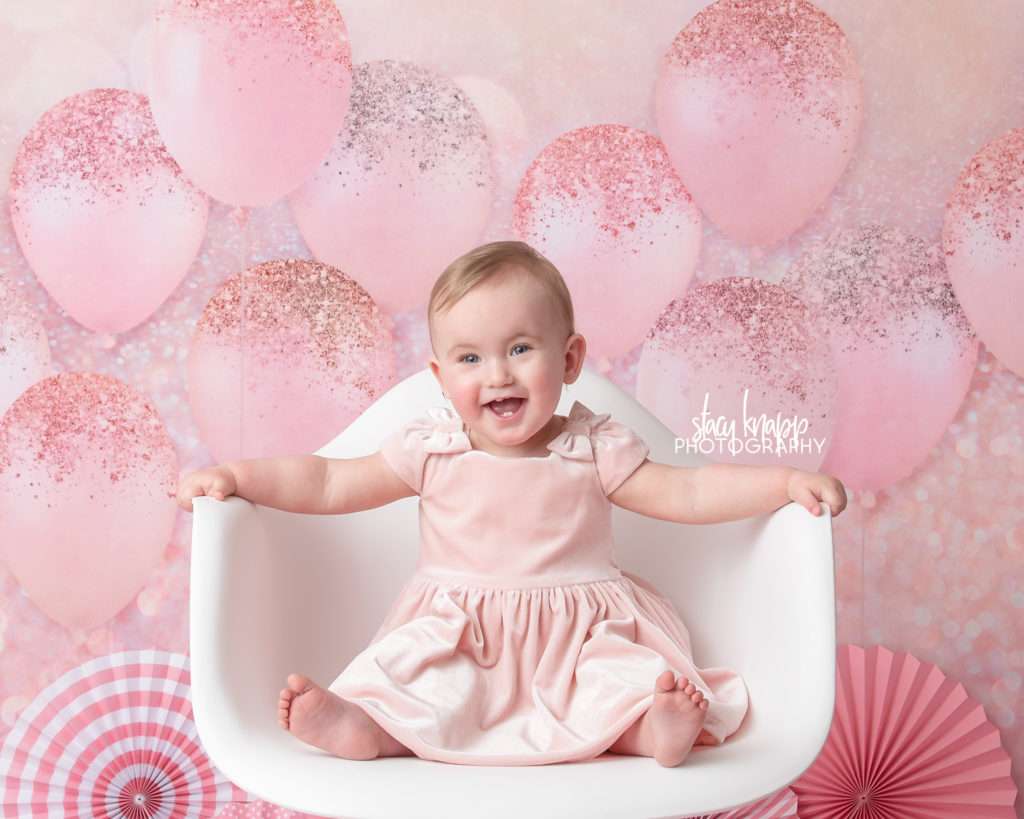 Photo of one-year-old girl birthday session with pink balloons and pink dress