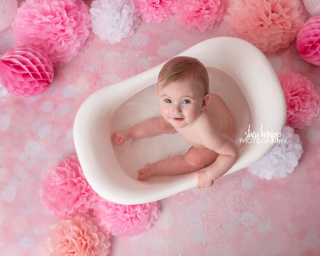 Photo of one-year-old girl birthday splash session with pink balloons