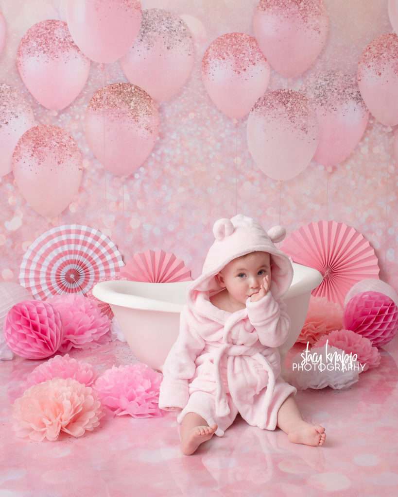 Photo of one-year-old girl birthday splash session with pink balloons