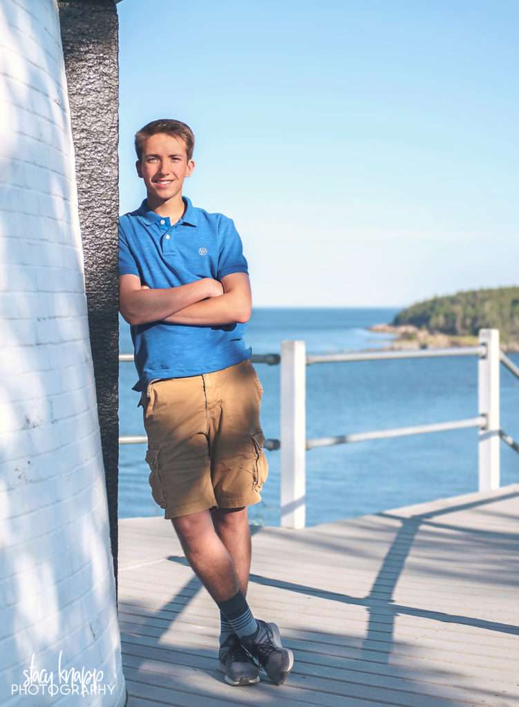 High school senior boy leaning against light house