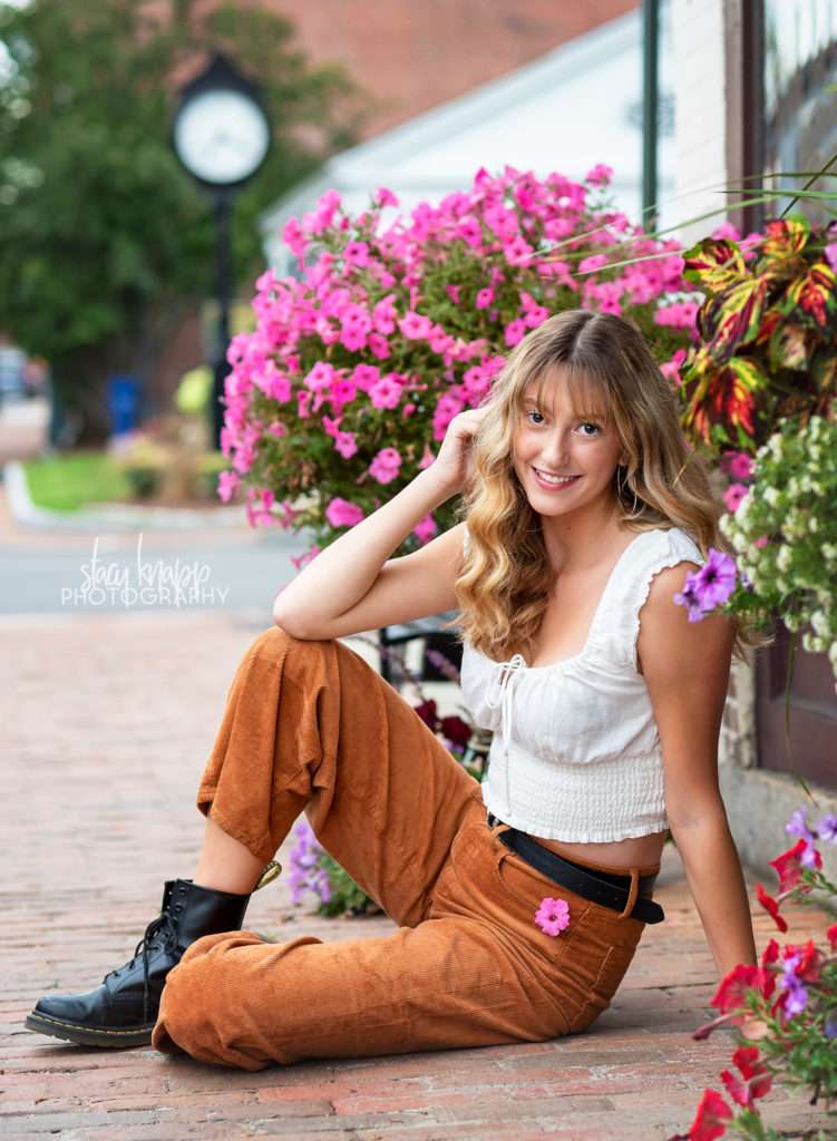 High school senior girl sitting in front of flowers