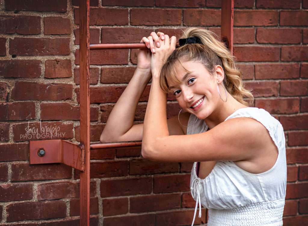 High school senior girl posing with arms on ladder
