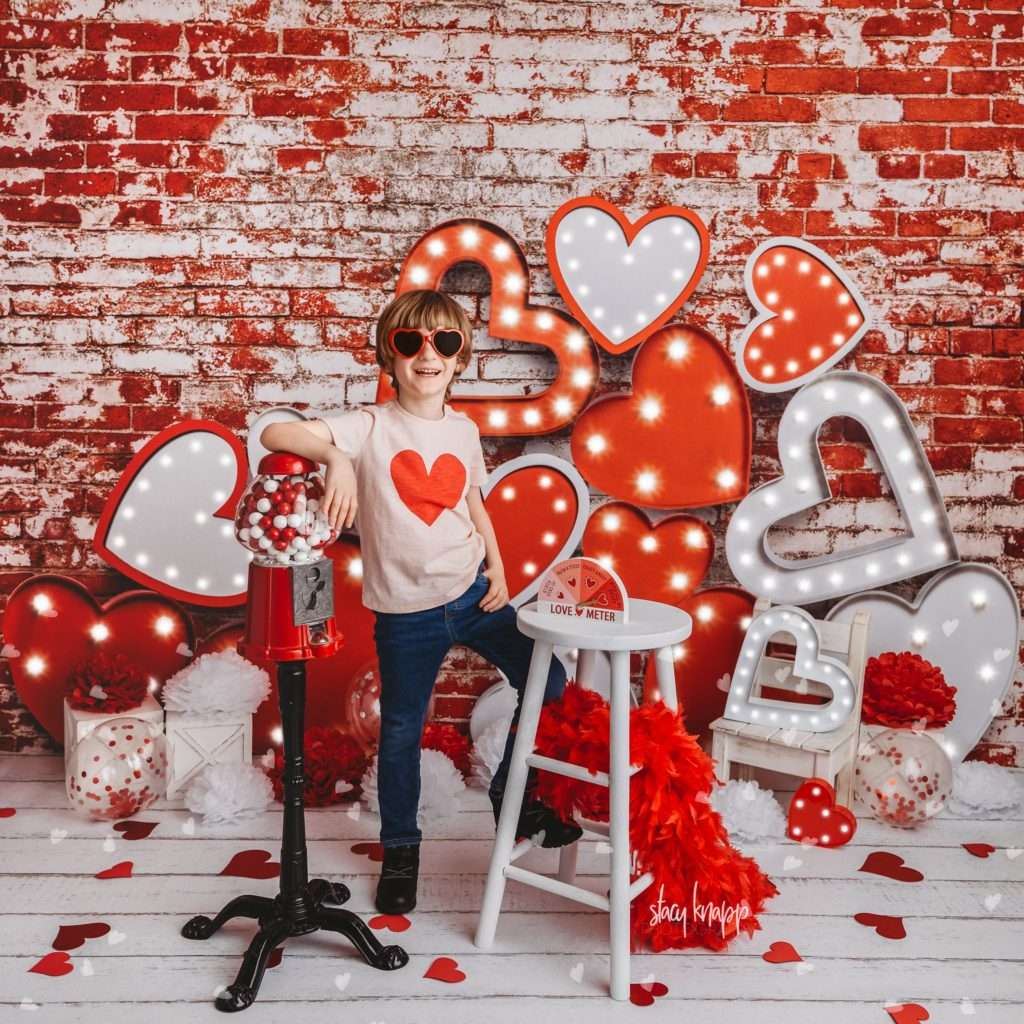 Young boy celebrating valentines day at Stacy Knapp Photography standing with gumball machine