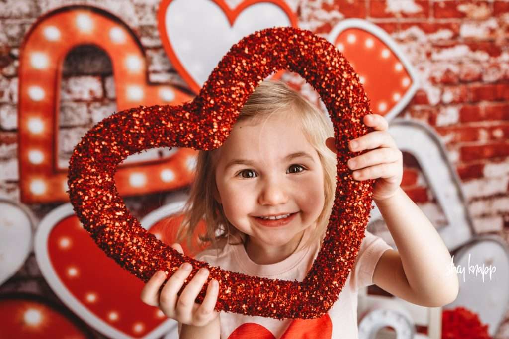 Young girl celebrating valentines day at Stacy Knapp Photography face in heart