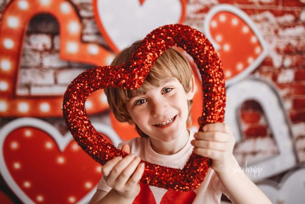 Young boy celebrating valentines day at Stacy Knapp Photography face in heart