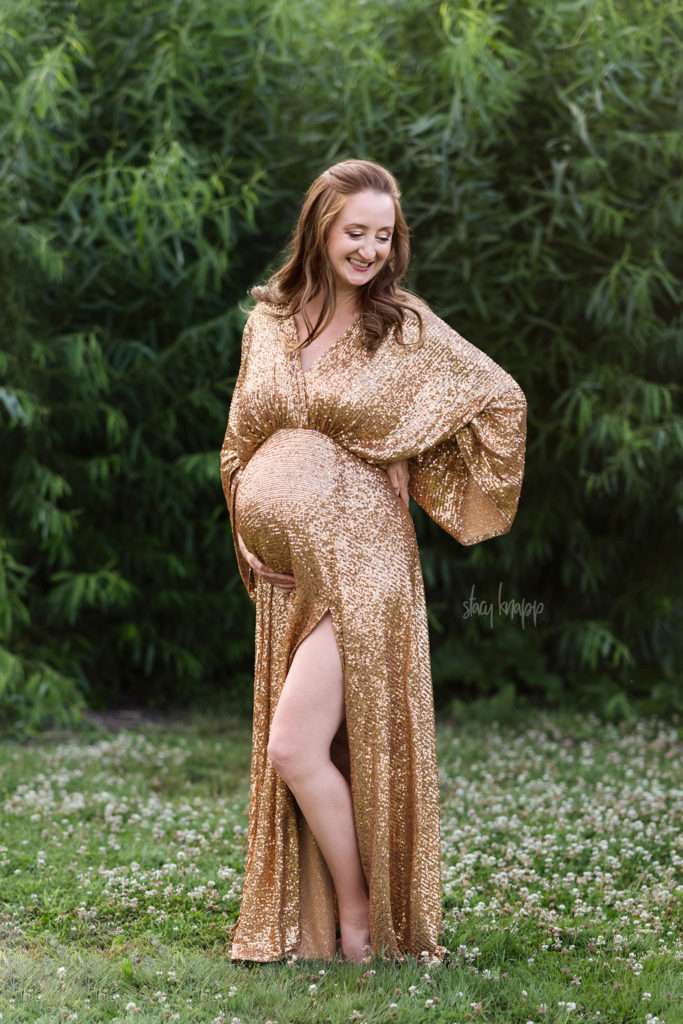 Maternity photo of a pregnant mother in a gold glittery gown at the Viles Arboretum in Augusta, Maine by photographer Stacy Knapp Photography