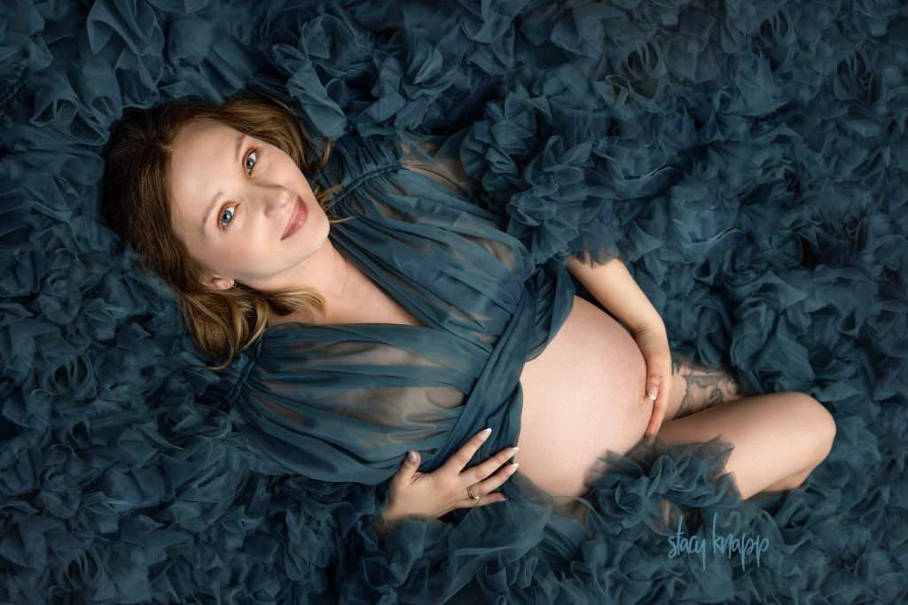 Photo of a pregnant Maine mother taken from above wearing a teal luxury maternity gown by photographer Stacy Knapp Photography