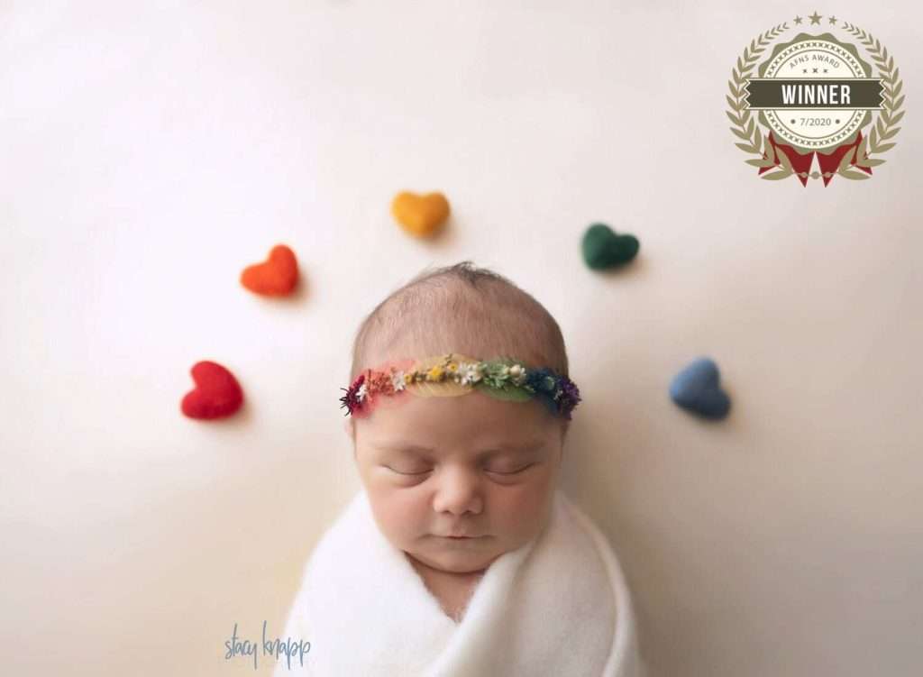 Newborn photography winners - baby girl with rainbow of hearts above her head
